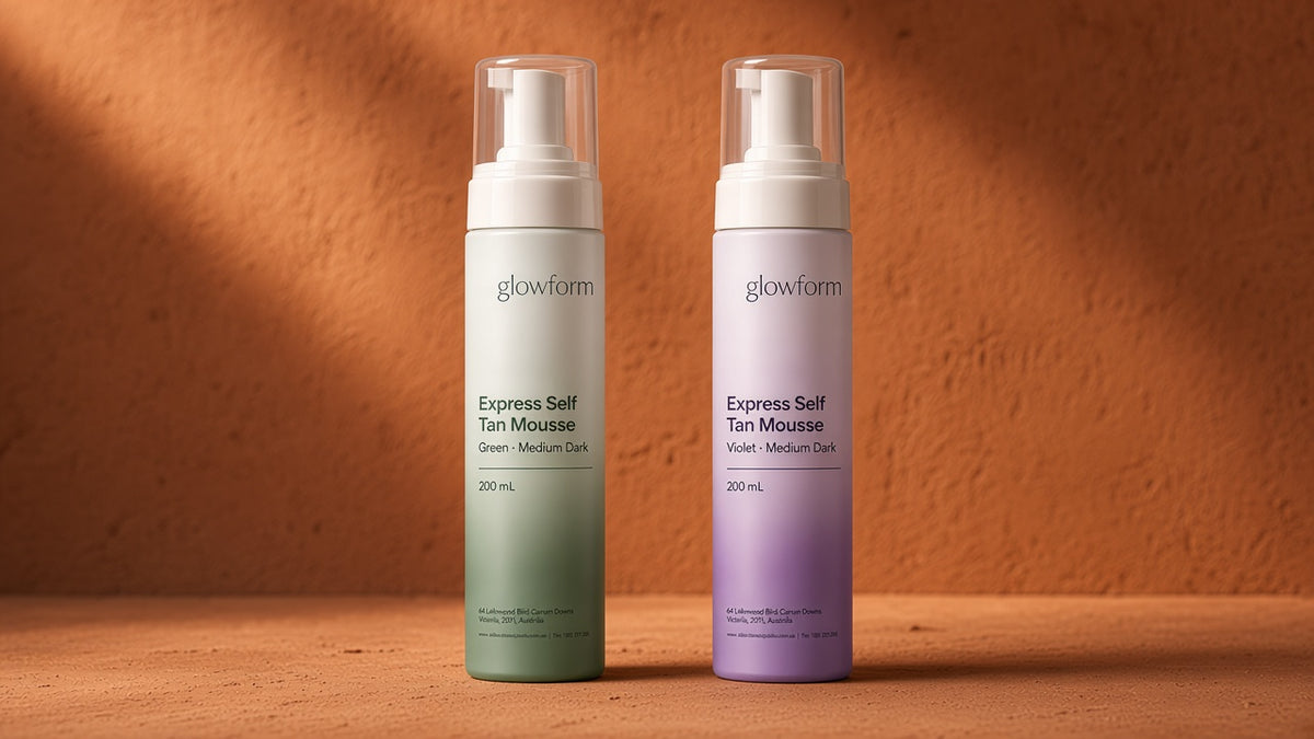 Glowform Express Self Tan Mousse, Medium Dark, in the green and violet bases against a textured terracotta wall