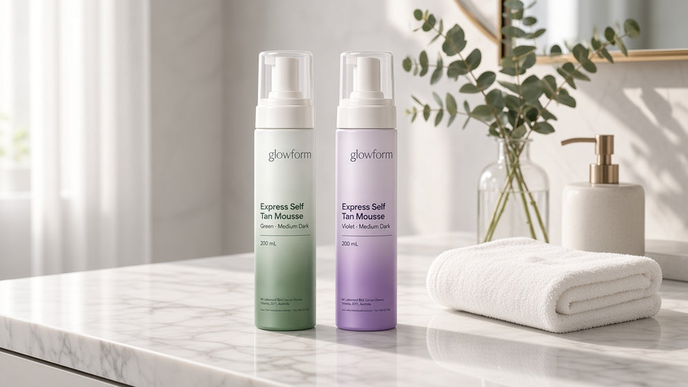 Green and violet Medium Dark mousses on a marble vanity beside a folded towel
